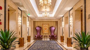 A luxurious hotel lobby with a marble floor, ornate chandeliers, and two large purple armchairs. - Oriental Ventura (Lishui)