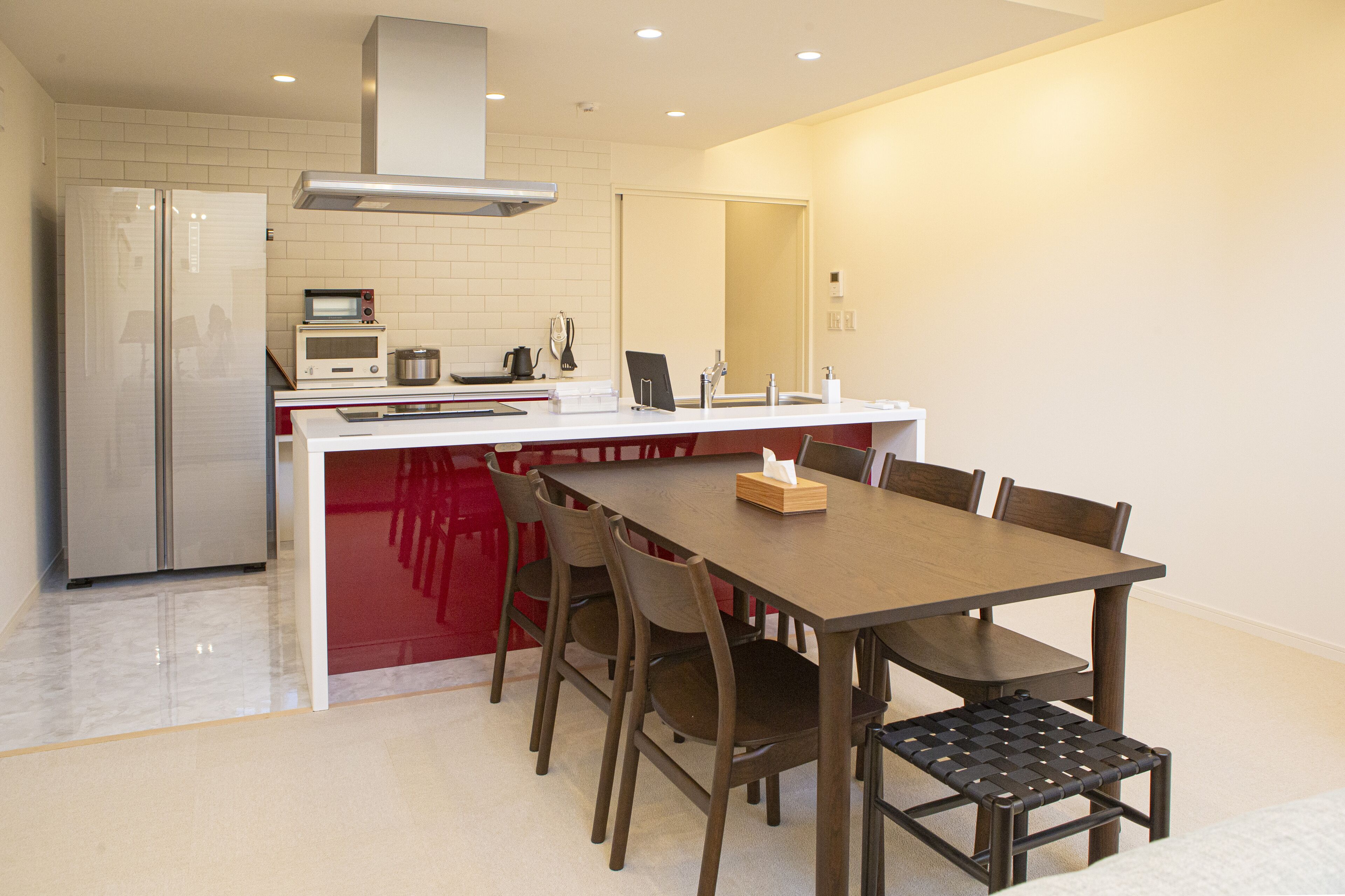 A compact kitchen with a refrigerator, microwave, and stove. There is a dining area with a table and chairs.