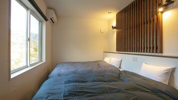 A bedroom with a large bed, a window, and a wall-mounted light fixture.