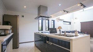 A modern kitchen with a central island, built-in appliances, and a large window providing natural light. - Setsu (Fujikawaguchiko)