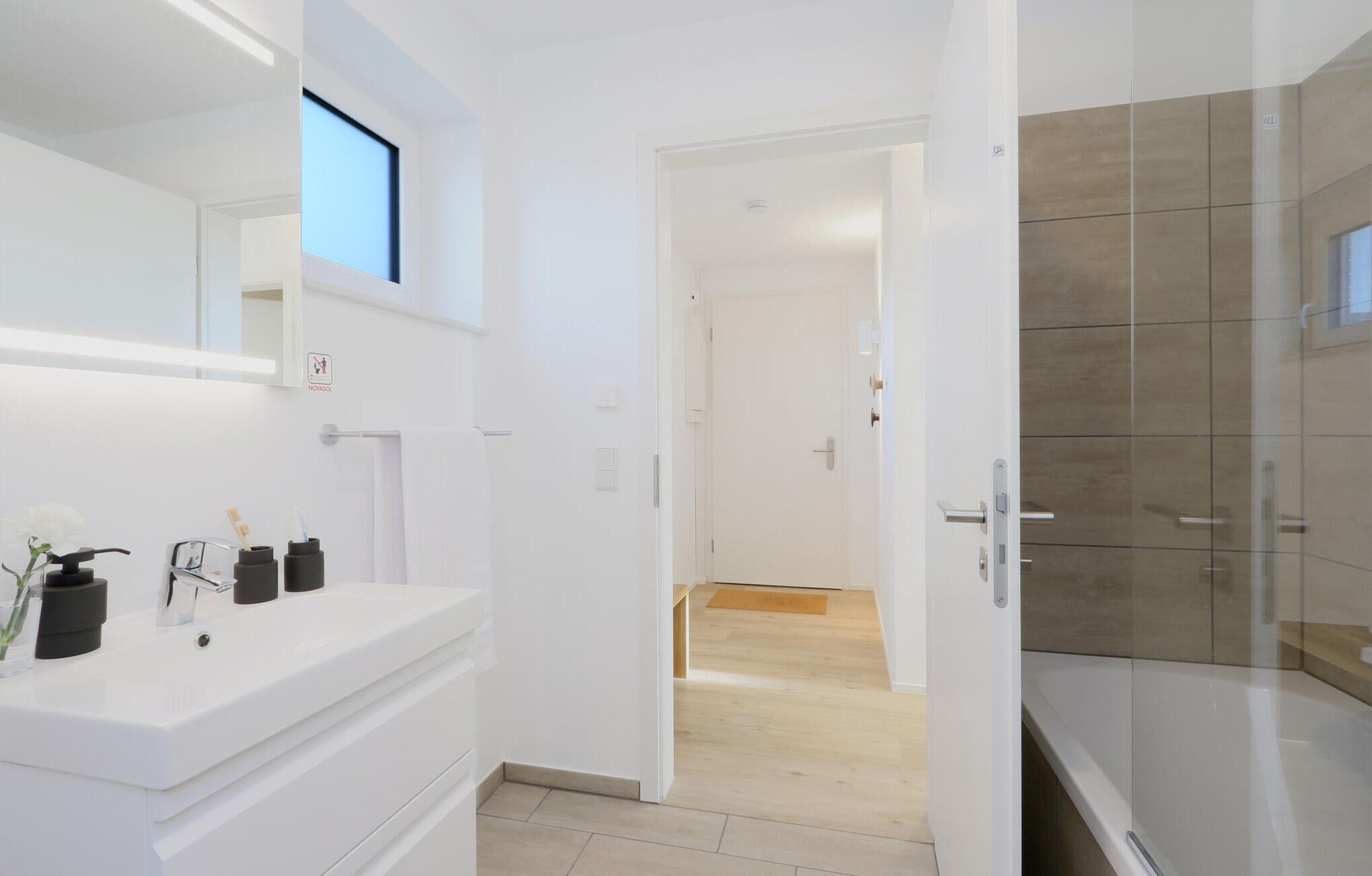 A modern bathroom with a white vanity, a mirror, and a shower area with glass doors.