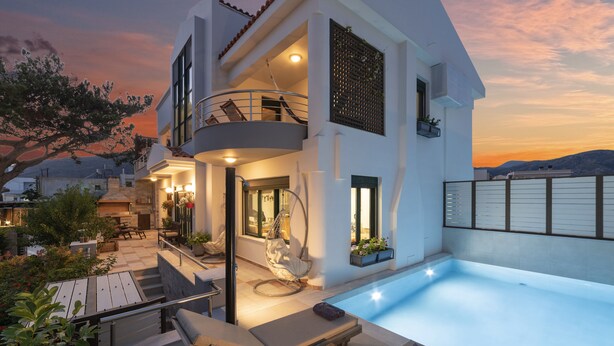 A modern two-story house with a swimming pool, outdoor seating, and a balcony.
