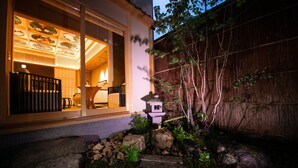 A traditional Japanese-style house with a wooden exterior, a stone pathway, and a small garden with rocks and plants. - Tenyu (Kyoto)