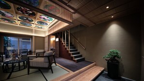 A traditional Japanese interior with tatami flooring, a low wooden bench, a staircase, and a bonsai tree. - Tenyu (Kyoto)