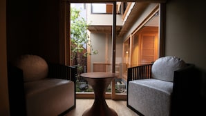 A room with two sofas, a round table, and a view of a garden through a sliding door. - Tenyu (Kyoto)