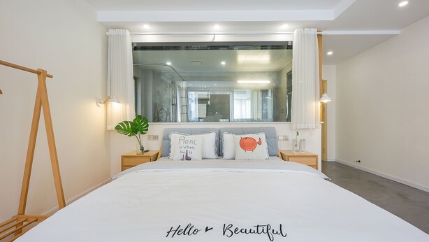 Un dormitorio moderno con una cama grande, una escalera de madera, un espejo y una ventana con cortinas.