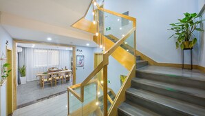 Un interior de hotel moderno con una escalera, un comedor y una planta.