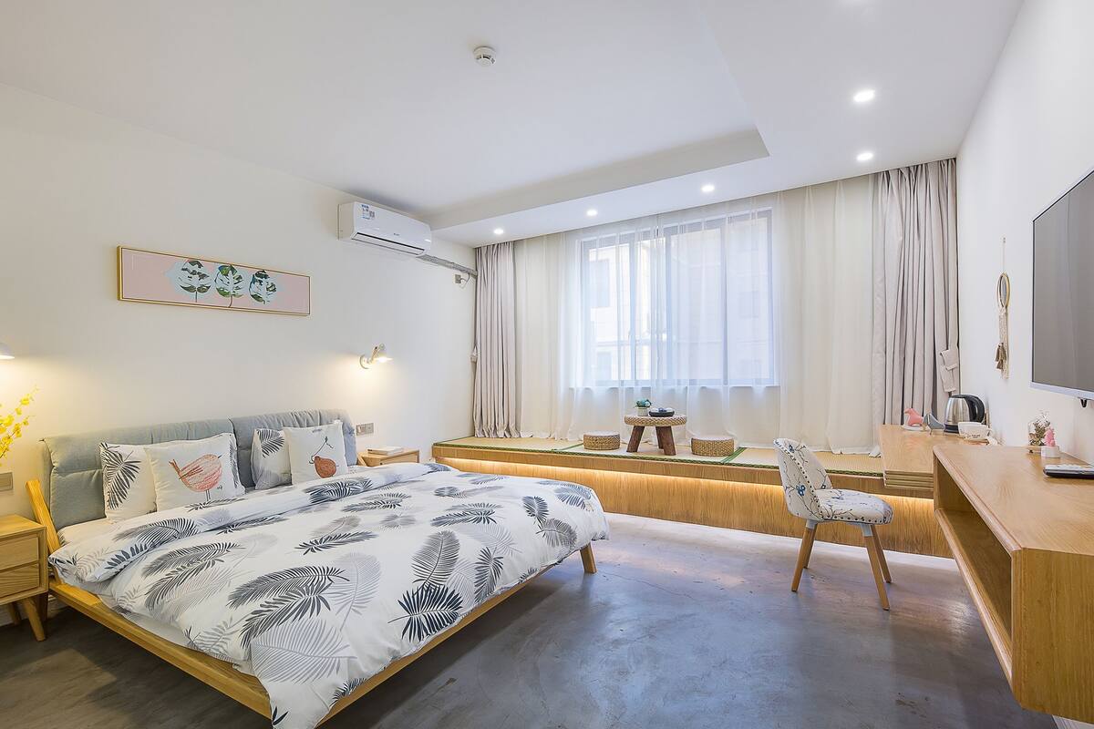 Un dormitorio moderno con cama, mesitas de noche, un escritorio y una televisión.