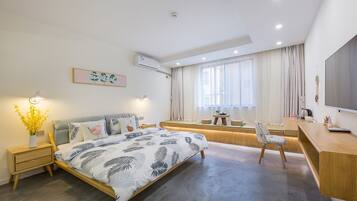 A modern bedroom with a bed, bedside tables, a desk, and a TV.