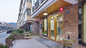 Un hotel con fachada de ladrillo, terraza de madera y zona de estar al aire libre.