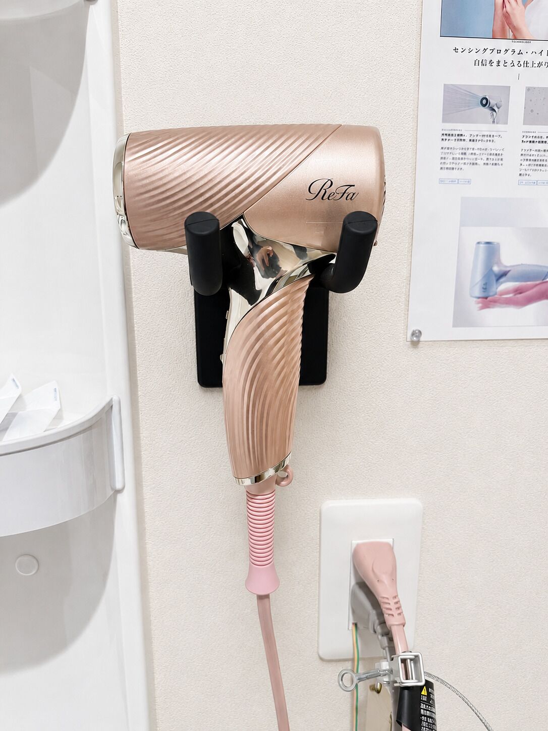 A hair dryer mounted on a wall with a control panel and a cord.