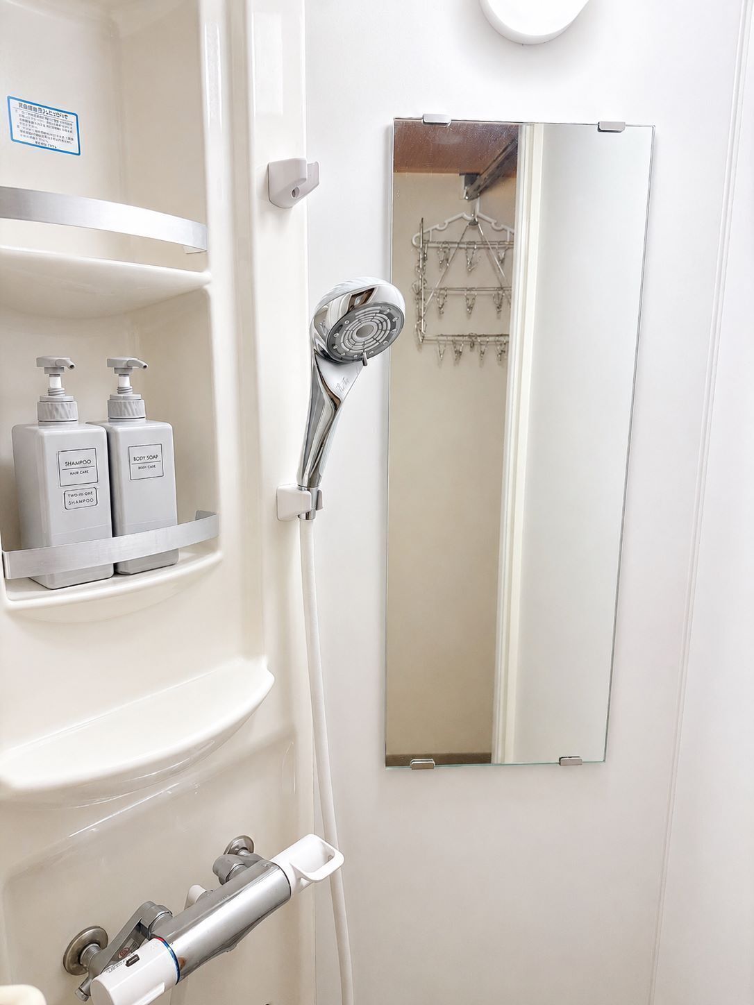 Une salle de bain avec une douche, un miroir et des articles de toilette rangés sur des étagères.