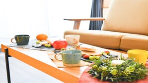 Un tavolo da pranzo con un sottopiatti, una ciotola di frutta e un bouquet di fiori.