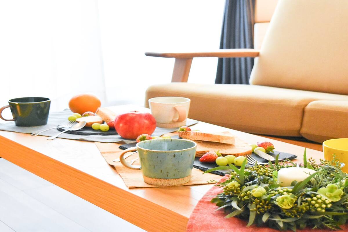 A dining table with a placemat, a fruit bowl, and a floral arrangement.