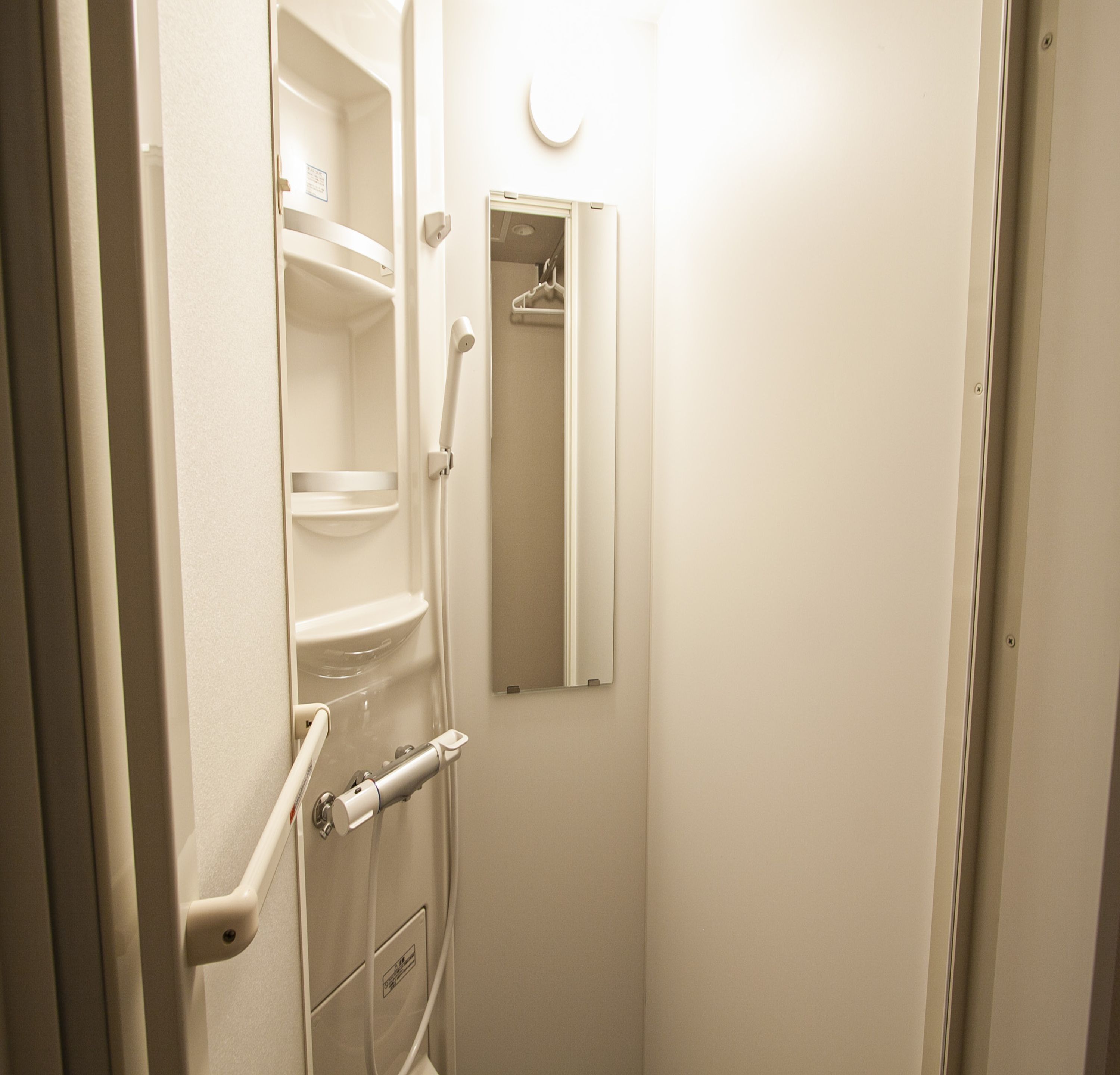 A small, white bathroom with a toilet, a sink, and a mirror.