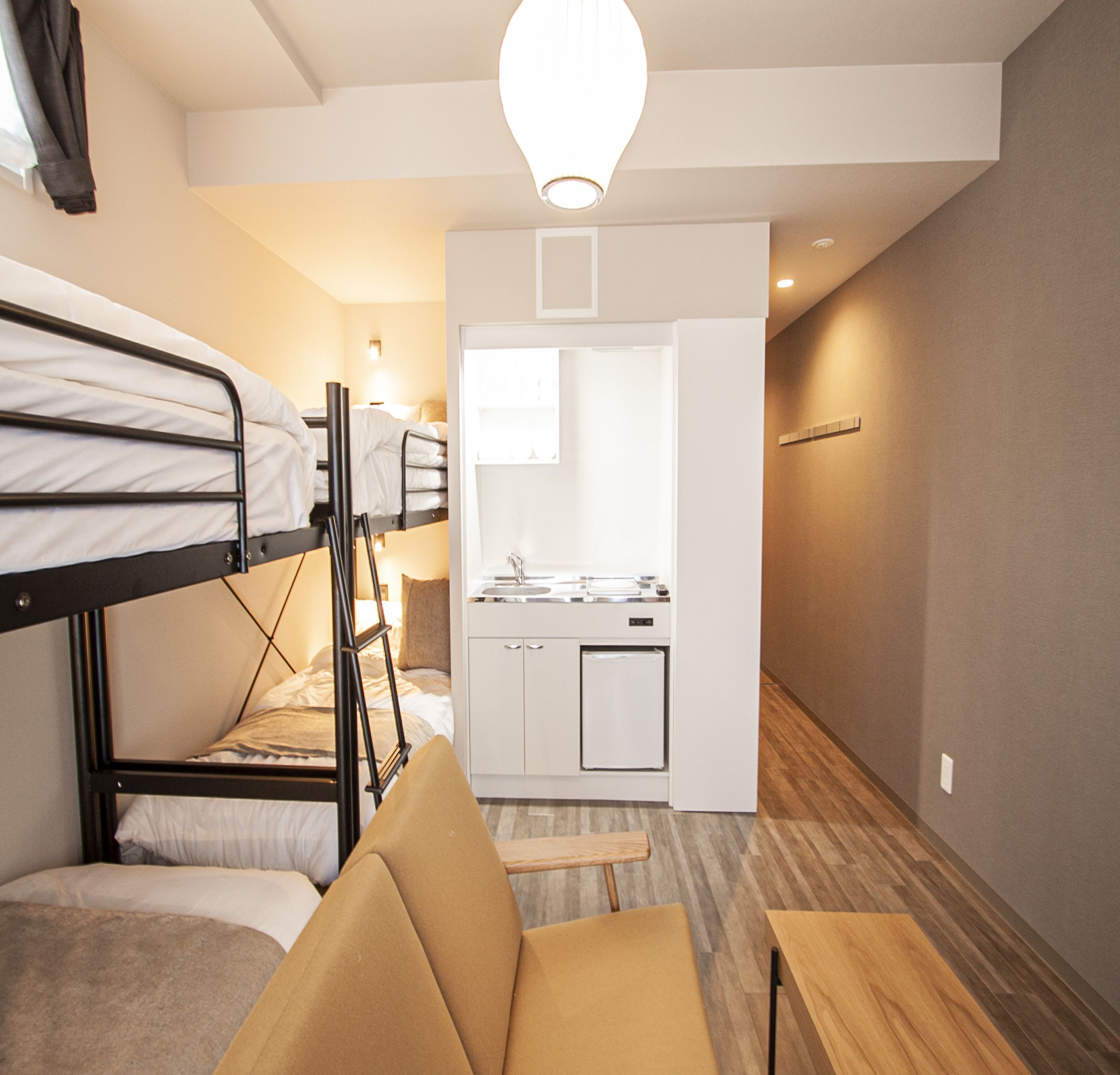 Una habitación pequeña con literas, kitchenette y un rincón de descanso.