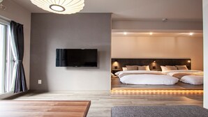 Una moderna camera d'albergo con un letto grande, una TV a schermo piatto fissata al muro e un pavimento in legno.