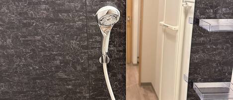 A bathroom with a shower, a mirror, a towel rack, and two bottles of shampoo.