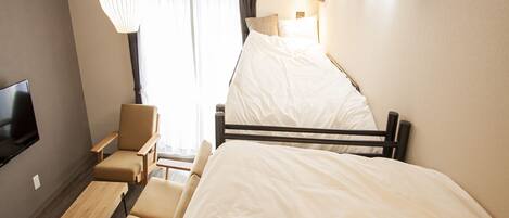 Une chambre d’hôtel de taille réduite, comprenant un lit simple, un bureau, une chaise, un téléviseur et un appareil de climatisation.