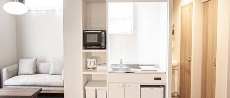 A compact kitchenette with a microwave, sink, and storage cabinets.