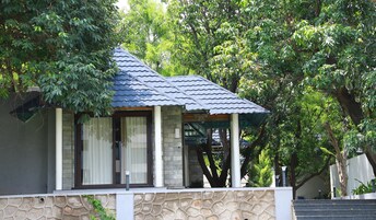 Un piccolo edificio con pareti in pietra, tetto a tegole, ampie finestre e un portico coperto.