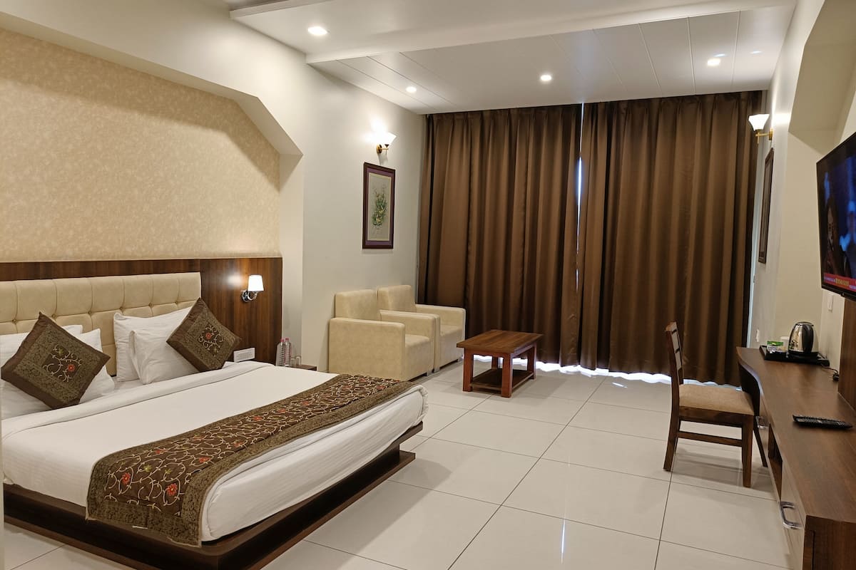 Une chambre d’hôtel avec un grand lit, un bureau, une chaise et un téléviseur.