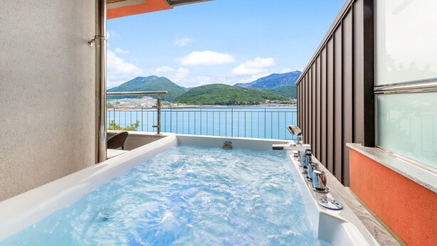 A hot tub with a view of a lake and mountains.