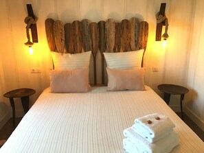 Ein Bett mit gestreifter Bettdecke, zwei Kissen und einem Stapel gefalteter Handtücher.