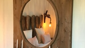 Um espelho de madeira rústico fixado na parede, com moldura circular, rodeado por velas e um adorno de parede rústico.