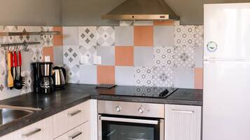 A modern kitchen with a stainless steel range hood, a built-in oven, and a white refrigerator.