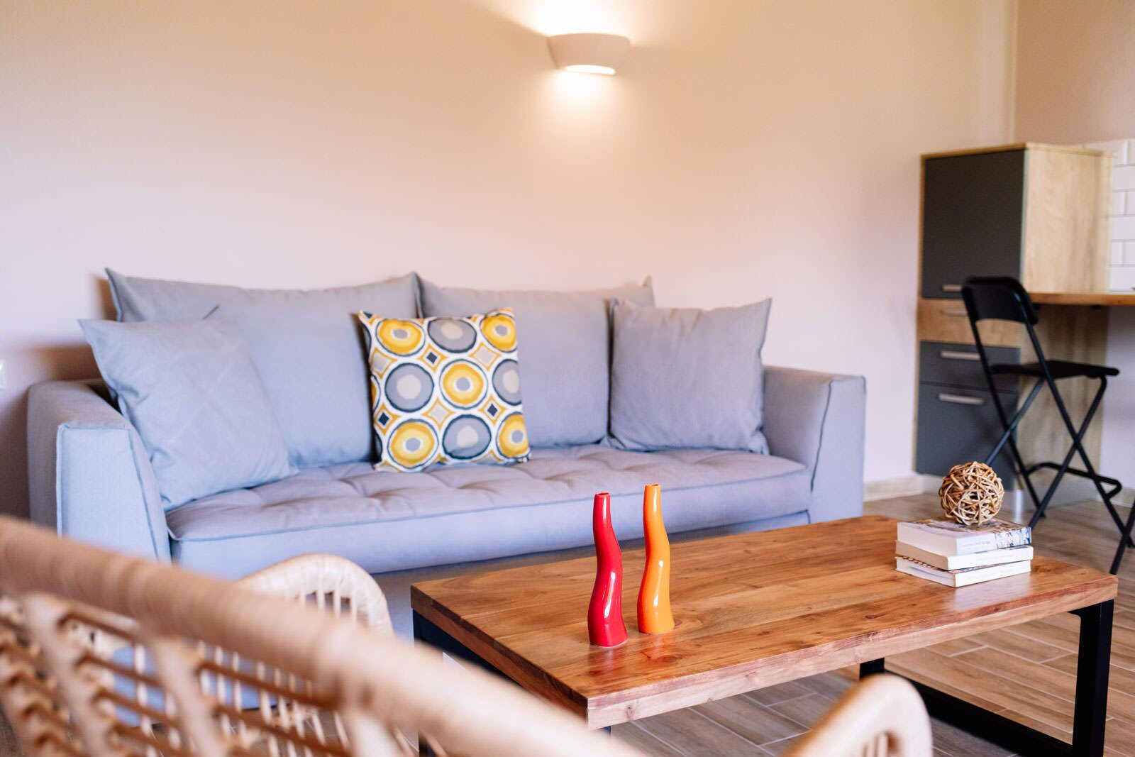A living room with a light blue sofa, patterned pillows, a wooden coffee table, and a small bookshelf.
