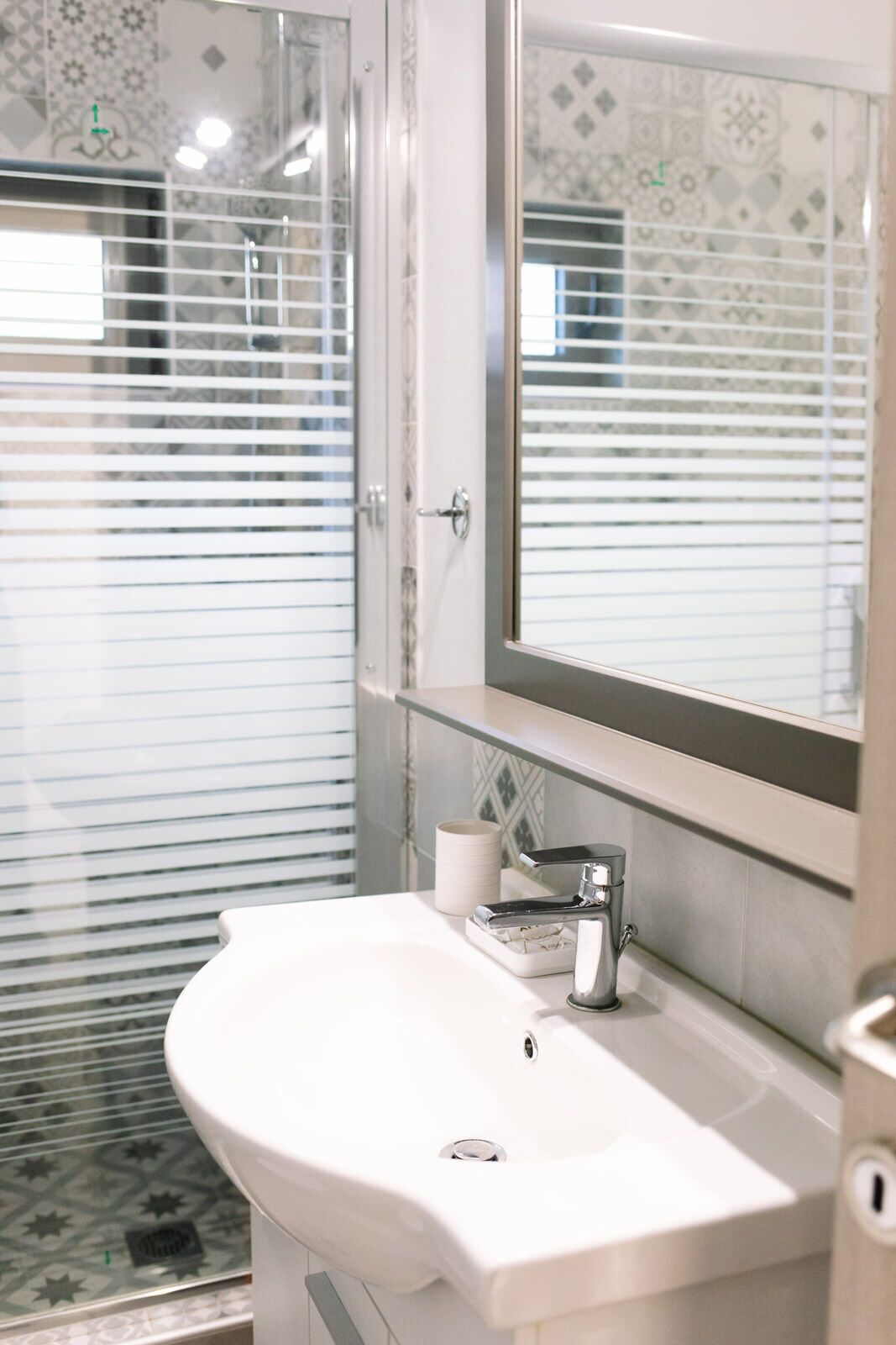 A bathroom with a white sink, a mirror, and a shower with a glass door.