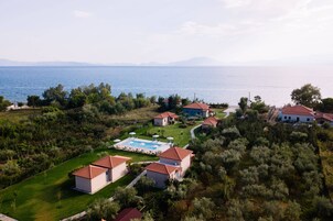 Vista aérea de una propiedad costera con varias edificaciones, una piscina y vistas al mar.