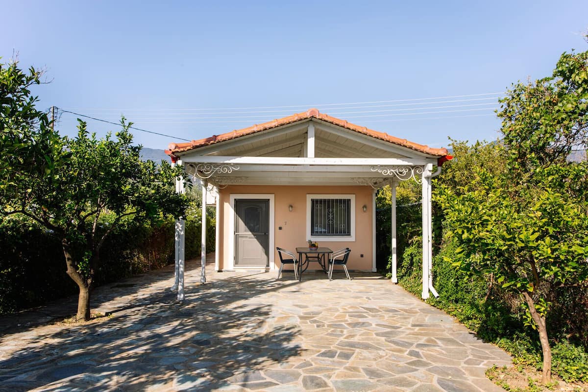A house with a stone pathway leading to a covered patio with a table and chairs.