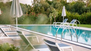 Une piscine avec des chaises longues et des parasols.