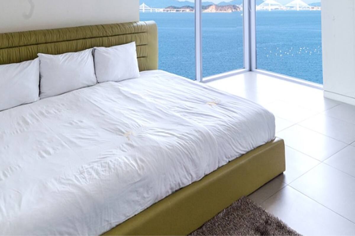 A bedroom with a large bed, a view of the sea, and a modern design.