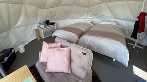 Eine Zeltunterkunft mit zwei Betten, einem kleinen Tisch und einem Kleiderständer.