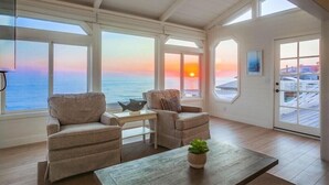 Ein geräumiges Zimmer mit großen Fenstern und Meerblick, ausgestattet mit zwei Sofas und einem kleinen Tisch.