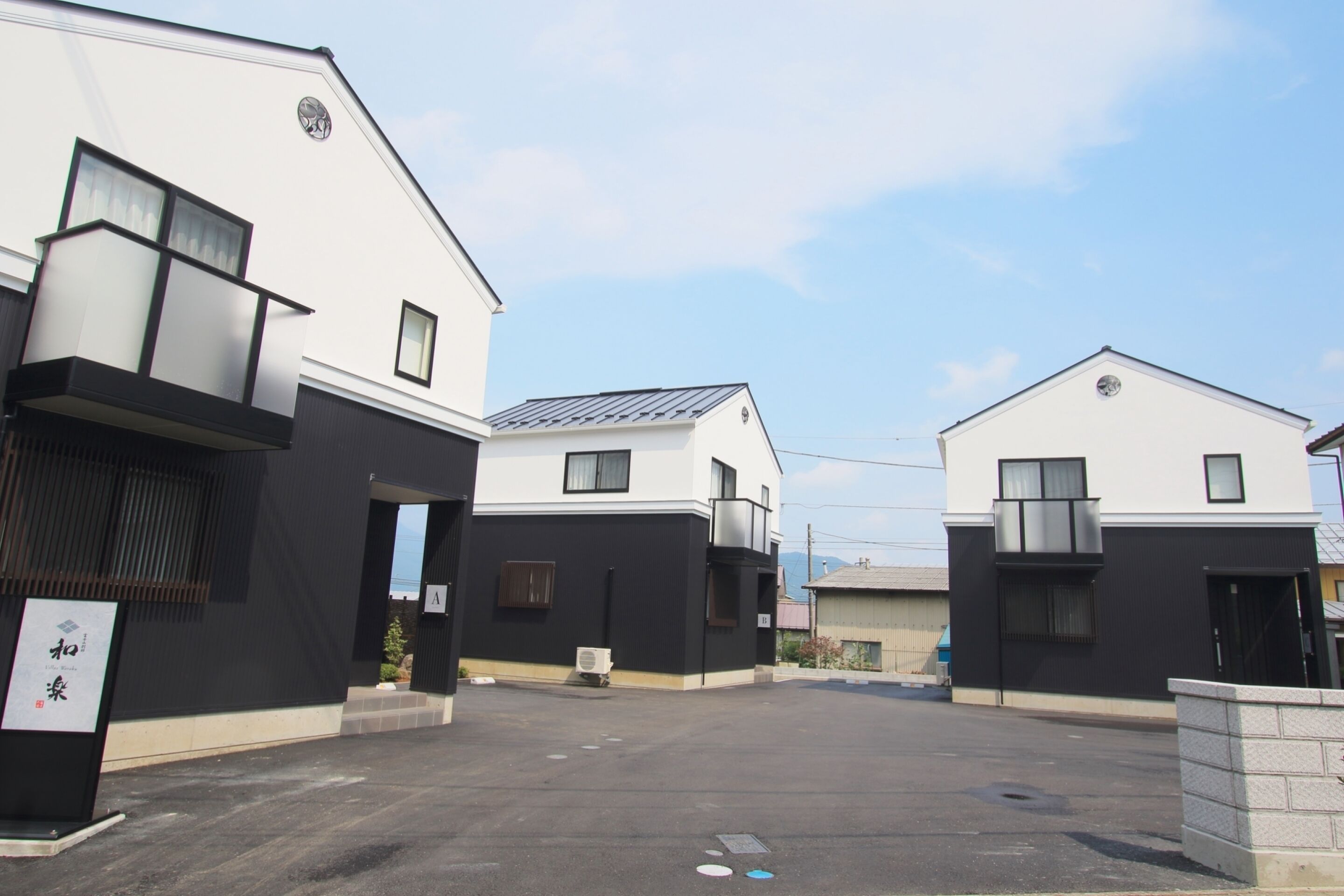 A parking lot with modern buildings, including a sign with Japanese characters.