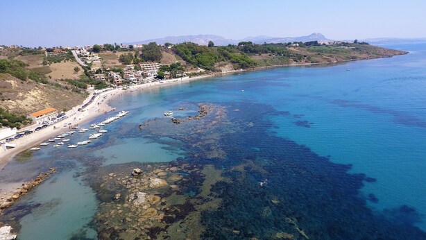 An aerial view of a coastal area with clear blue waters, rocky formations, and a beach with boats. - Holiday home in Sciacca Mare Tennis Soccer field, barbecue, wifi, kitchenette (Provincia di Agrigento)