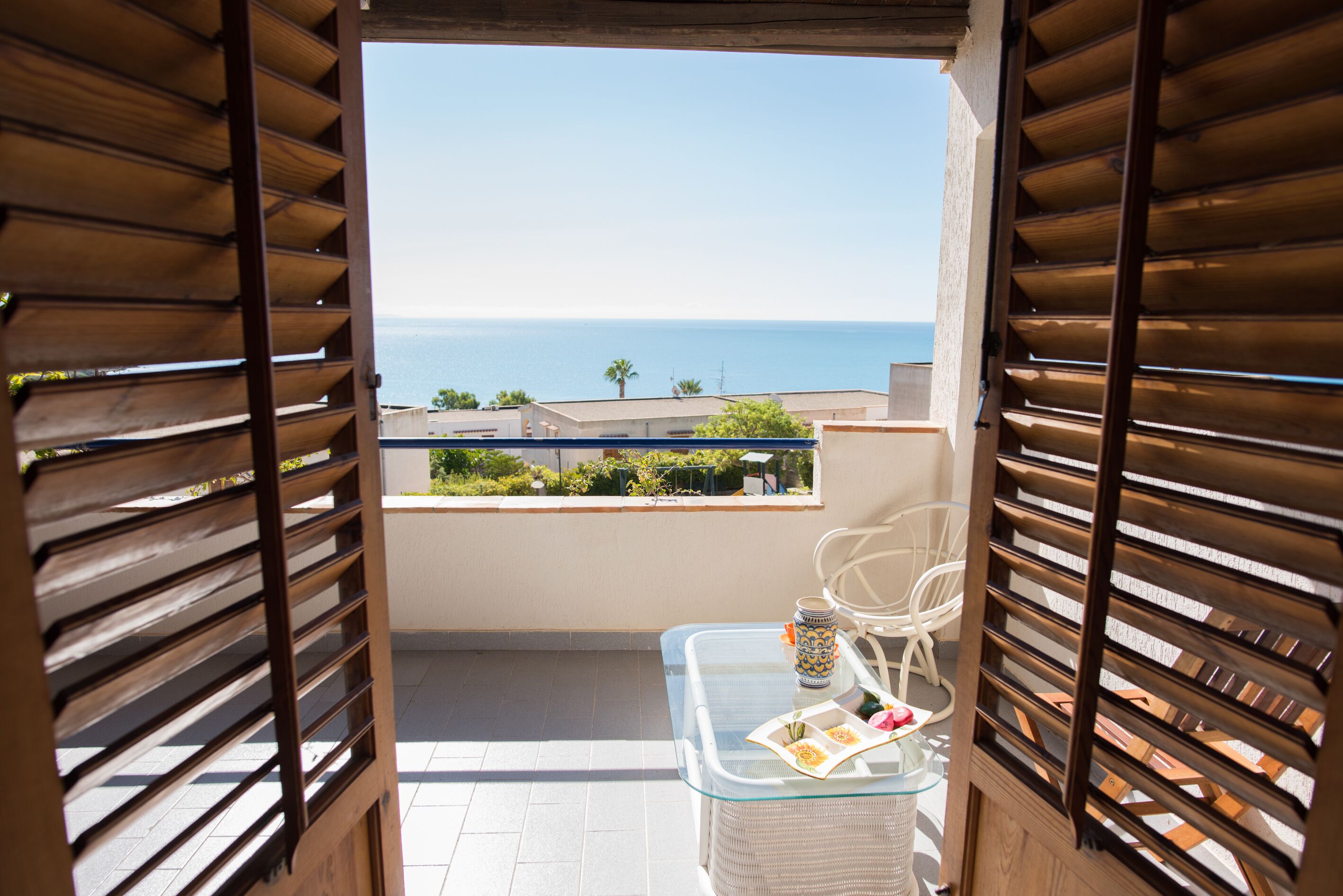 Ein Balkon mit einem Glastisch, einem Stuhl und einer Dekoration.