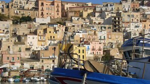 A harbor with boats docked and a densely packed hillside of buildings in the background. - Holiday home in Sciacca Mare Tennis Soccer field, barbecue, wifi, kitchenette (Provincia di Agrigento)