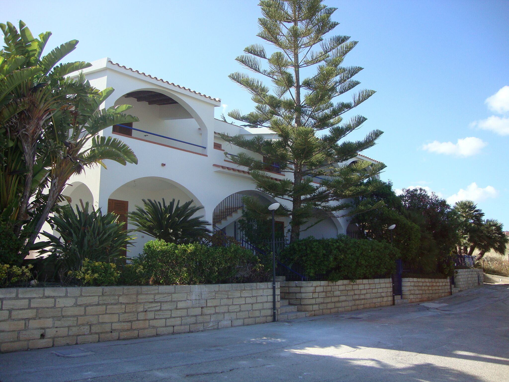 A building with a white facade, arched windows, and a staircase leading to an upper level.