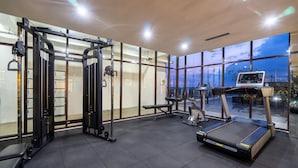 Ett modernt gym med löpband, styrketräningsmaskiner och en träningsbänk.
