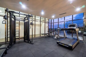 A modern gym with a treadmill, weight machines, and a bench.