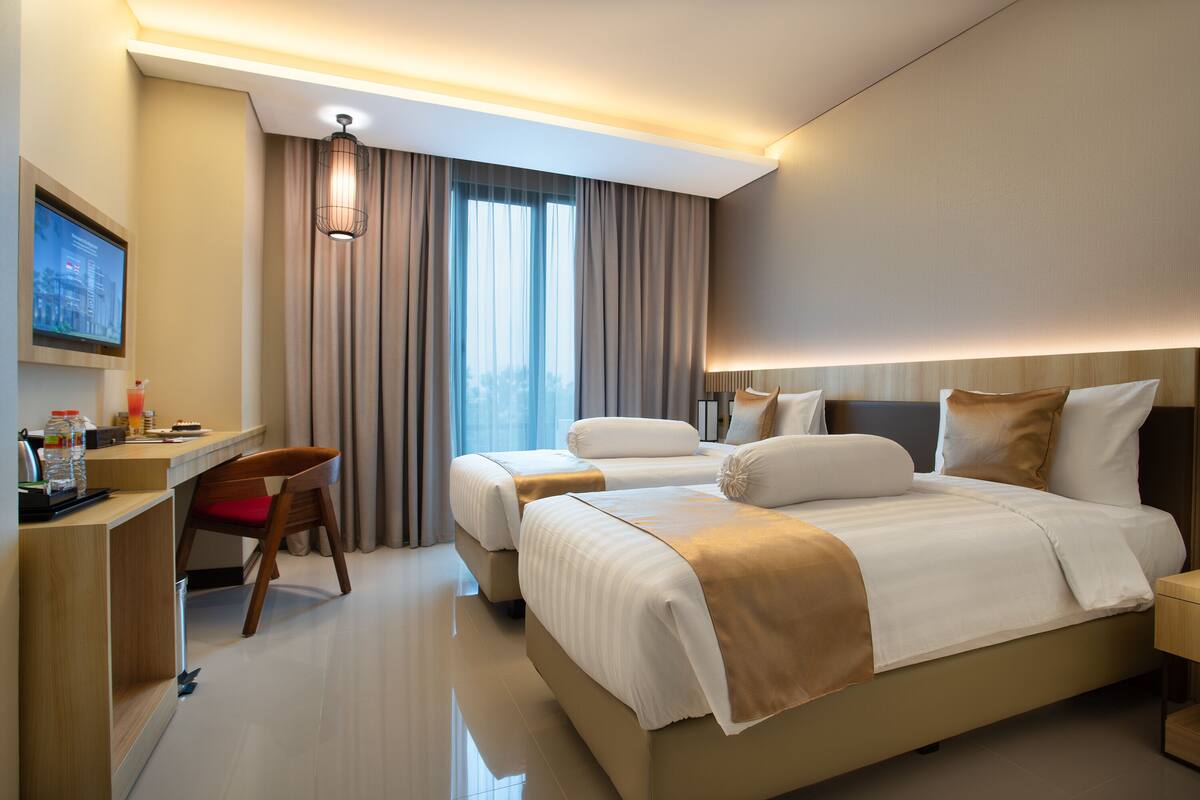 A modern hotel room with a large bed, a desk, and a television.