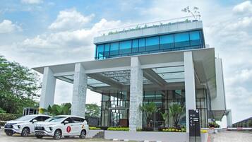 A modern hotel with a glass facade, white columns, and a covered entrance.