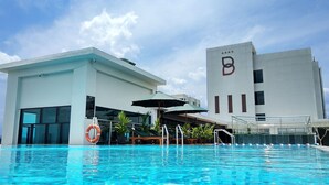 Ett modernt hotell med en swimmingpool, en livboj och parasoller.