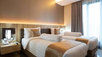 Habitación de hotel con dos camas, un escritorio con teléfono y un ventanal con cortinas.