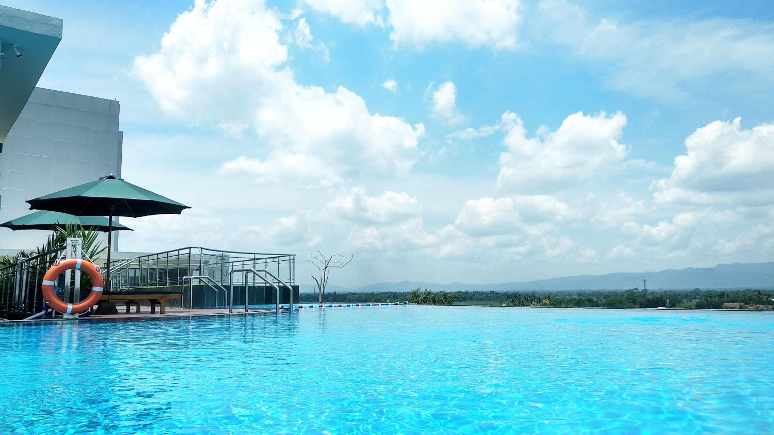 A swimming pool with a lifebuoy, a glass-enclosed structure, and a clear sky.